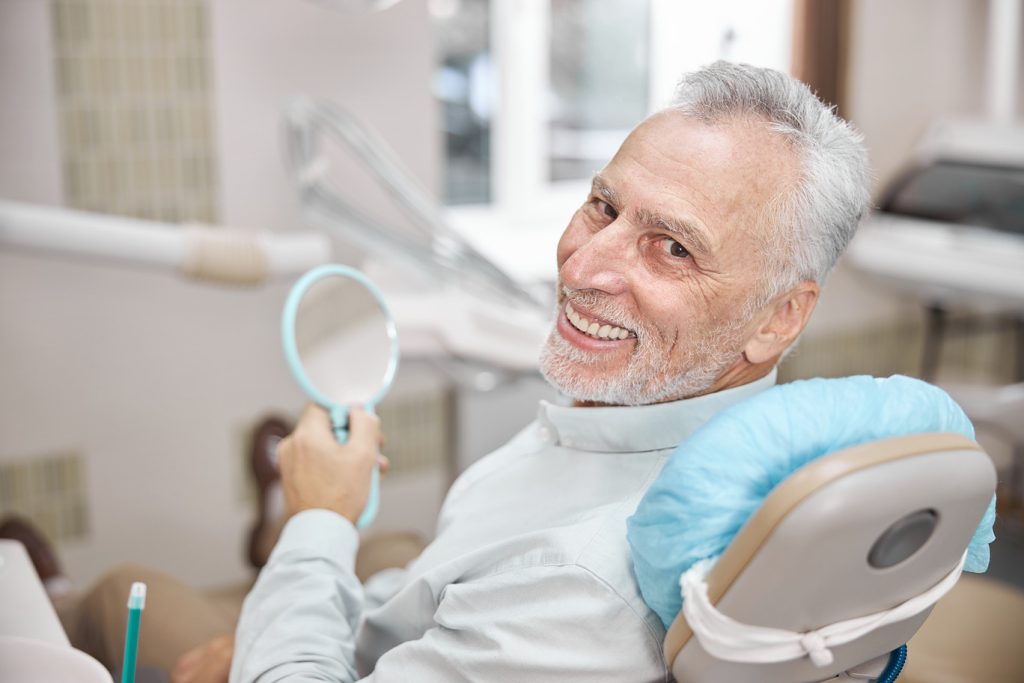 Elderly,Man,Smiling,While,Sitting,In,A,Dental,Chair,And