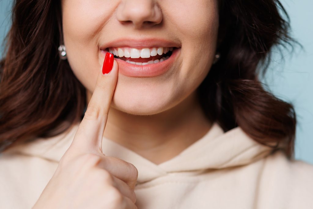 Happy,Girl,Showing,Toothy,Smile,,Pointing,Finger,At,Healthy,White