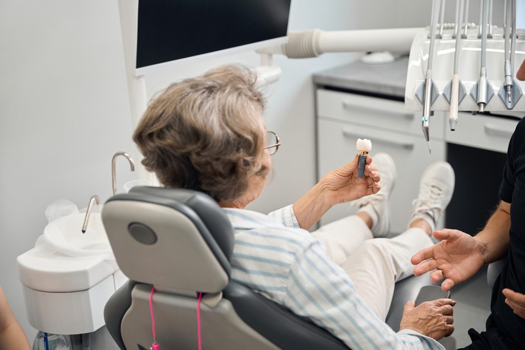 Lady,Holds,Model,Of,Dental,Implant,In,Hands