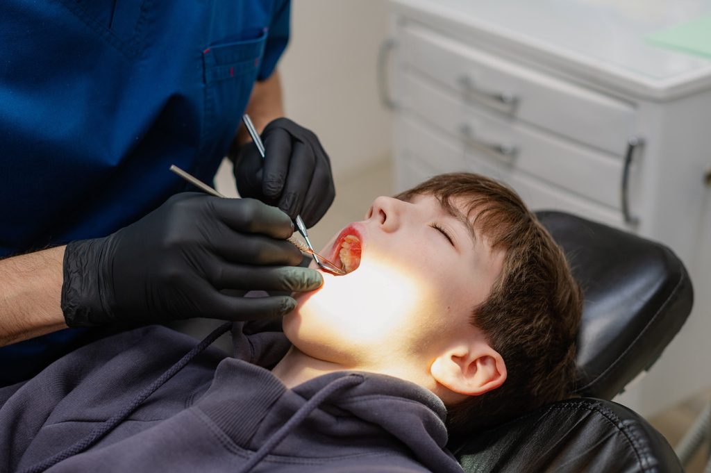 A,Dentist,Checks,The,Teeth,Of,A,Child,Who,Is