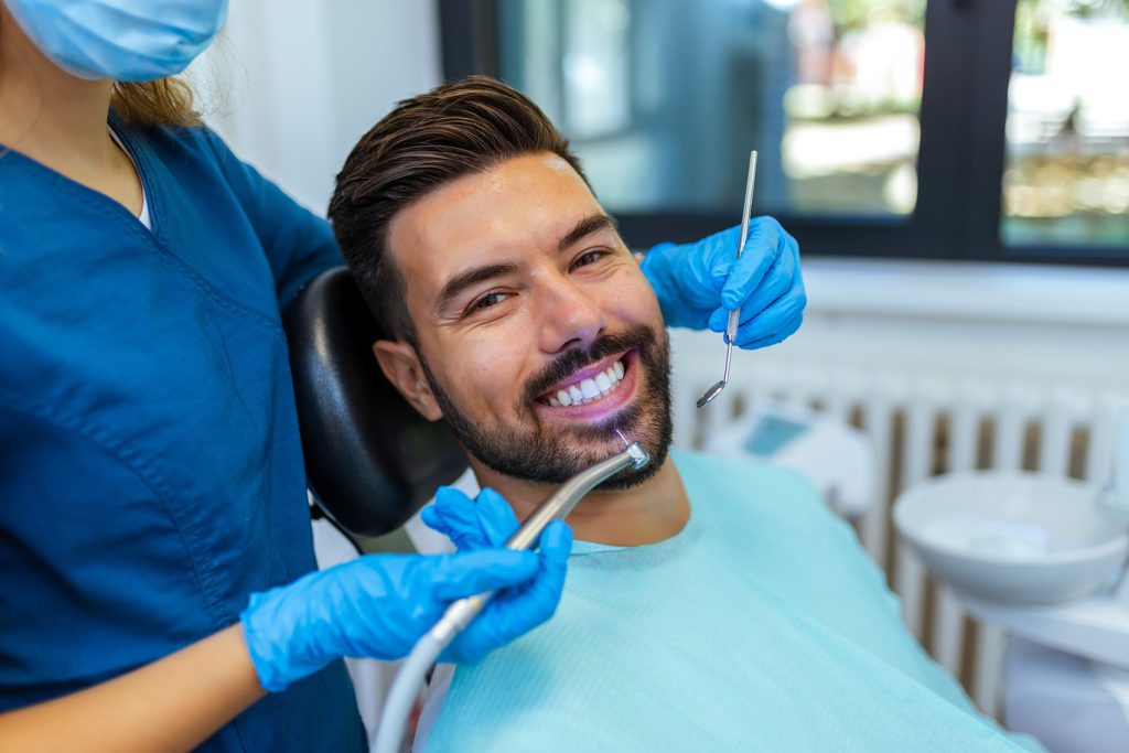 Female,Dentist,Performing,Dental,Treatment,On,Male,Patient,In,Modern