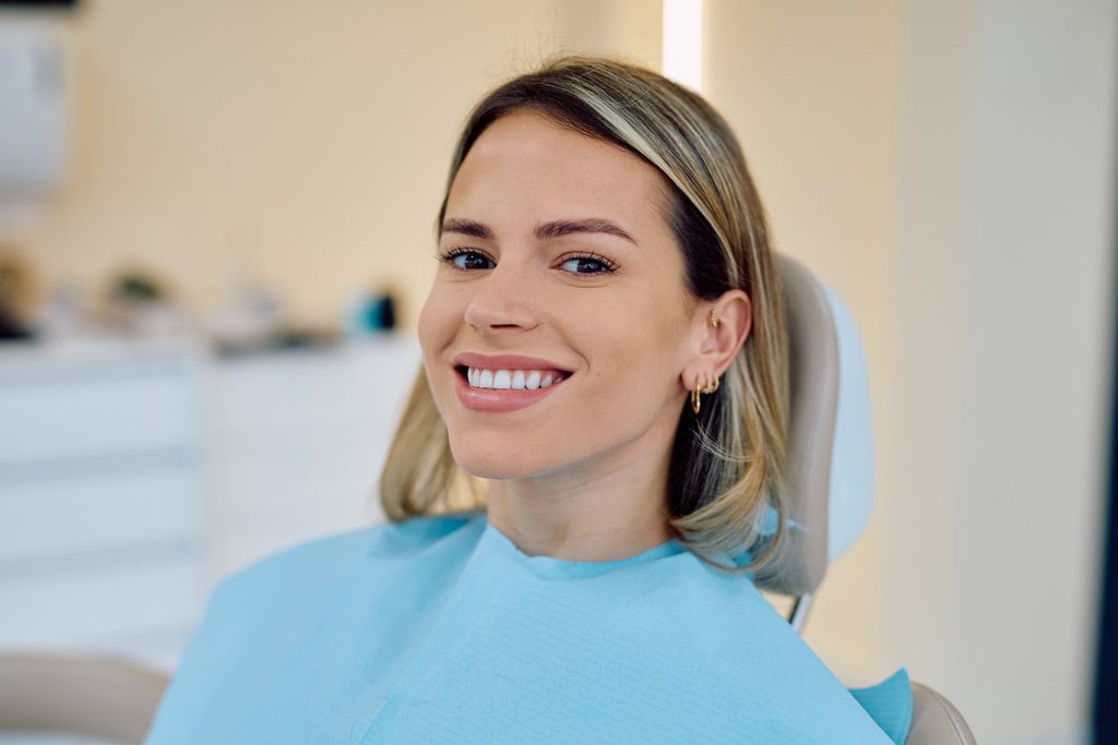 Smiling,Young,Woman,Sitting,In,A,Dental,Chair,,Wearing,A