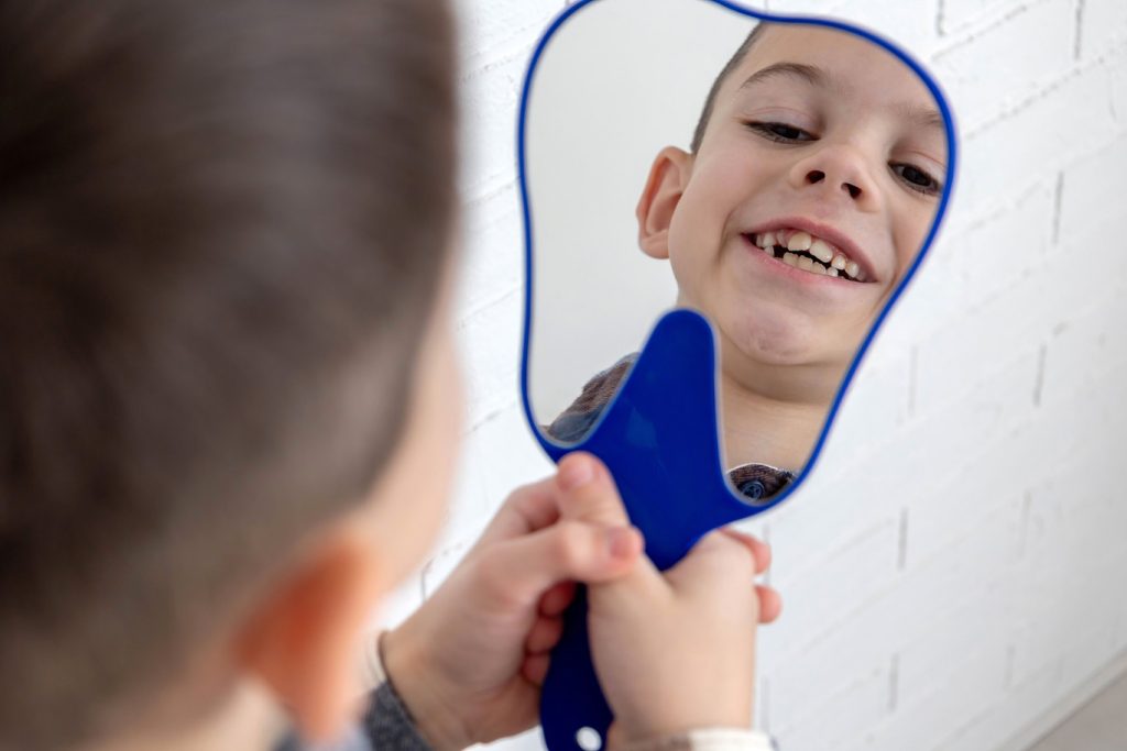 A,Boy,Looks,At,His,Teeth,In,The,Mirror,,Takes