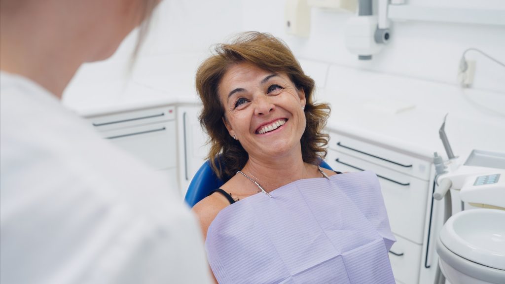 Mature,Woman,Patient,Smiling,Happily,,Looking,Up,At,The,Dental