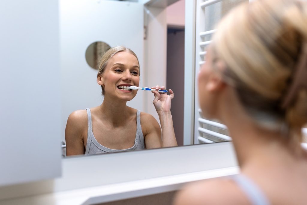 Woman,Brushing,Teeth,In,Bathroom,Mirror.,Dental,Hygiene,And,Oral