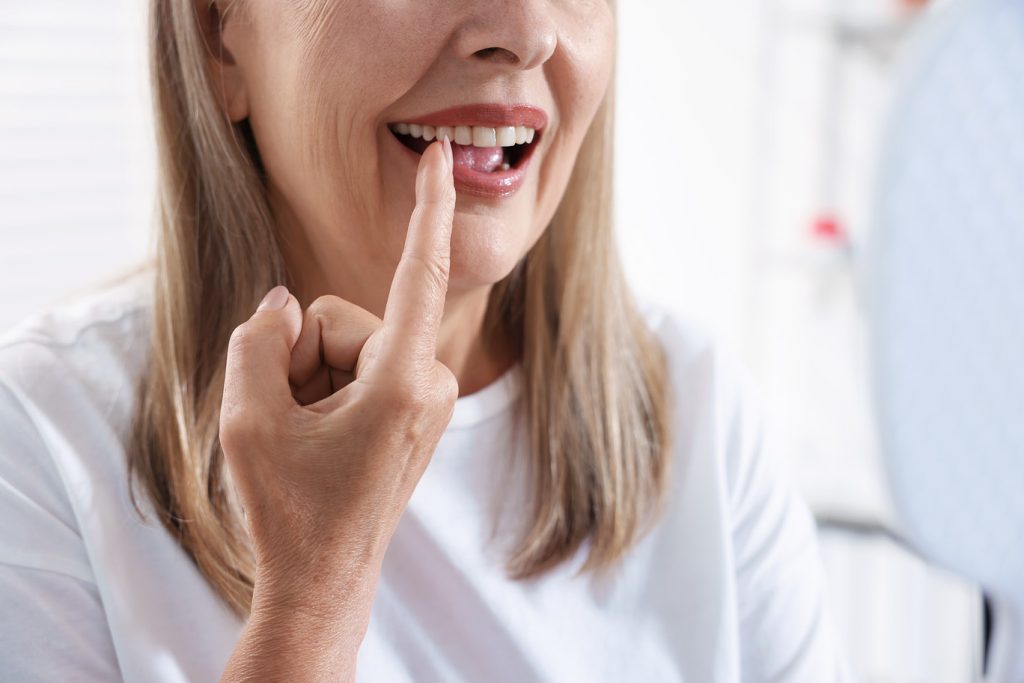 Senior,Woman,Looking,In,Mirror,At,Her,Teeth,With,Dental